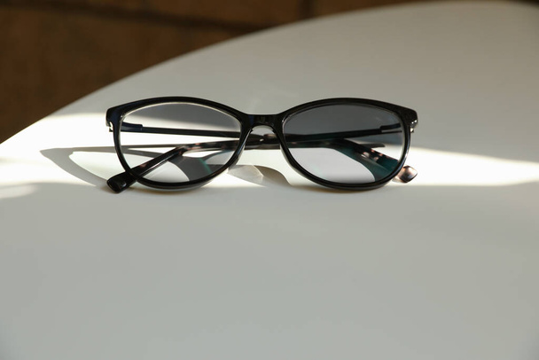 Stylish black eye glasses on white table. Space for text - Fotografie, Obrázek