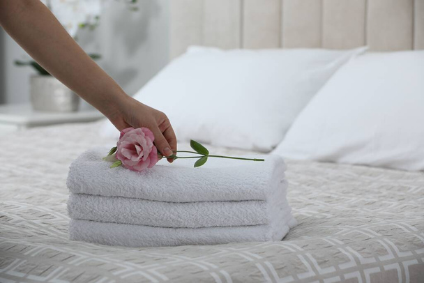 Woman putting Eustoma flower on folded towels in bedroom, closeup - Foto, imagen