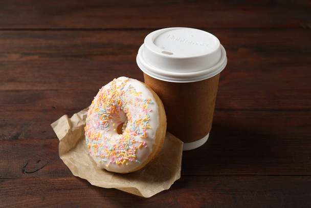 Yummy donut and paper cup on wooden table - Fotoğraf, Görsel