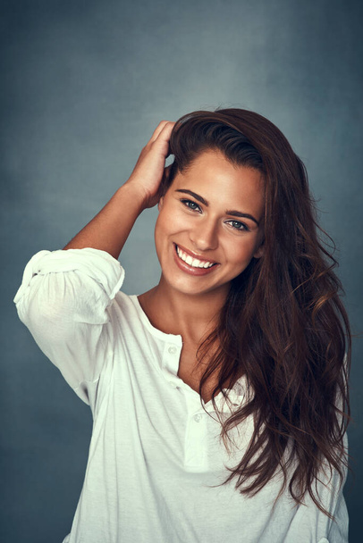 You never know whos falling in love with your smile. Portrait of a beautiful young woman smiling against a gray background in studio - Фото, зображення