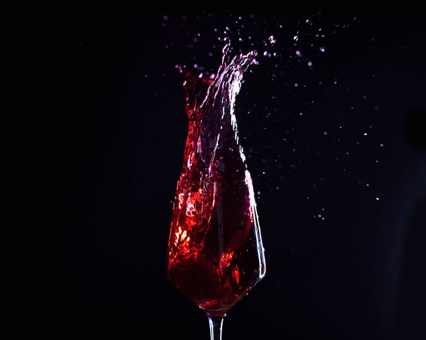 Wine, alcohol or drink glass and splash on black studio background for celebration, cheers or restaurant toast. Zoom, red creative texture or fruit beverage in liquid motion at event or birthday. - Foto, Imagen