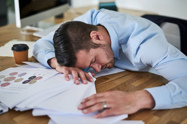 He ran out of steam. a tired young businessman with his head down on a pile of paperwork in an office - Foto, Imagem