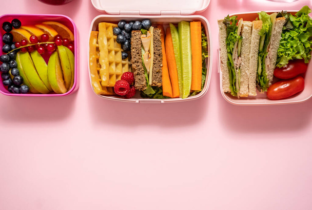 Здоровый обед на вынос. Сандвичи, фрукты и овощи упакованы в коробку для ланча. Концепция здорового питания. Вид сверху с плоской кладкой. - Фото, изображение