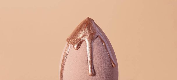 Closeup photography of beauty blender with dripping bronzer on it.Neutral beige background. - Photo, Image