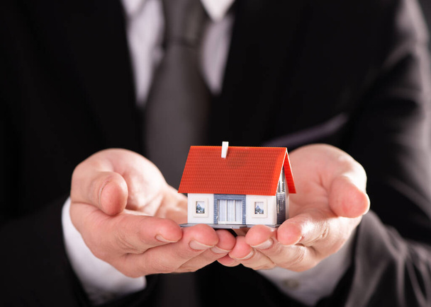 Businessman hand with model house - home concept - Photo, Image