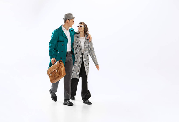 Stylish happy couple, young man and woman in 70s, 80s fashion style attires isolated on white background. Relationships, love, care and support. Concept of culture, art, music, style, ad - Zdjęcie, obraz
