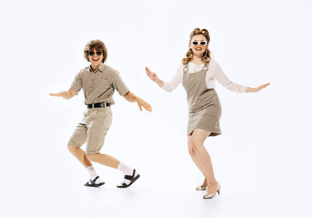 Delight. Expressive couple of dancers in vintage retro style outfits dancing social dance isolated on white background. Timeless traditions, 60s ,70s american fashion style. Dancers look excited - Fotografie, Obrázek