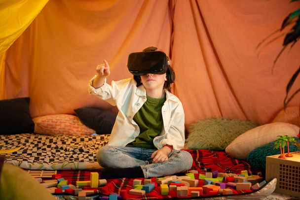 The boy are hanging out in a children s blanket tent indoors while playing with a vr headset and enjoying their time laughing together. - Foto, Imagem