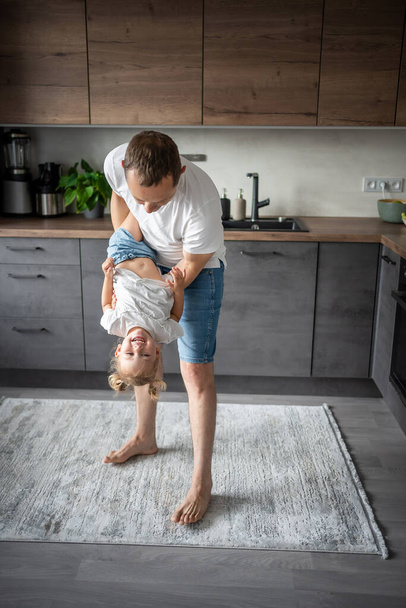 A happy father and little girl joyfully spending time in a modern kitchen. Happy family. Fathers day. High quality photo - Foto, imagen