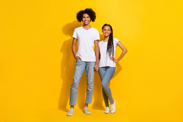 Full size photo of two positive cheerful partners hold hands have good mood isolated on yellow color background. - Foto, Imagen