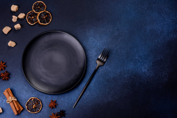 A piece of fresh delicious cake with nuts and chocolate on a black plate against a dark blue background. Desserts and sweets to the dinner table - Fotoğraf, Görsel