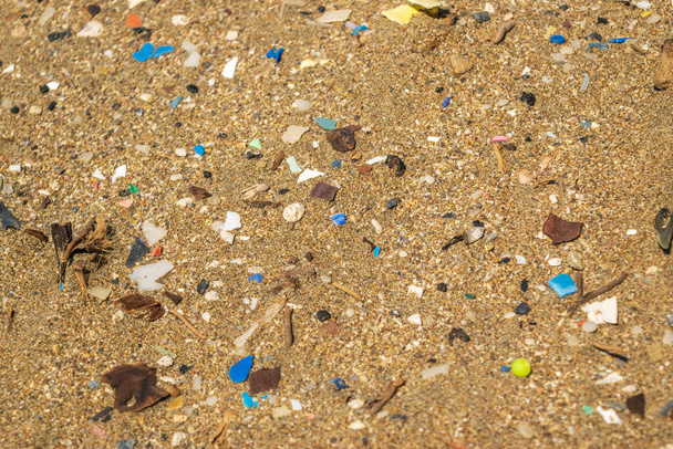 Microplastics on sand beach. Micro plastics garbage, tiny trash pieces, microplastic waste, dirty shore, small plastic parts on the coast of Greece, water pollution concept - Foto, Bild