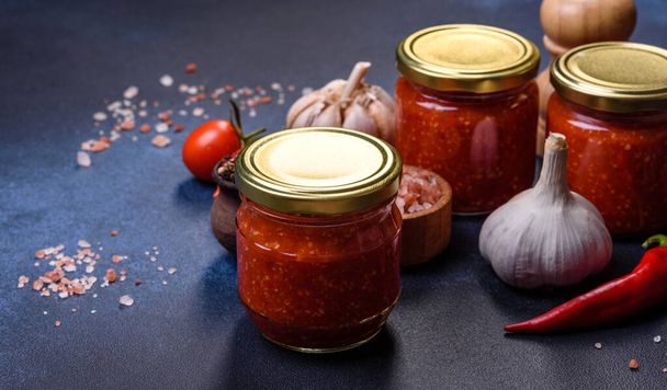 Tomato and chili sauce, jam, confiture in a glass jar on a blue stone background - Photo, Image