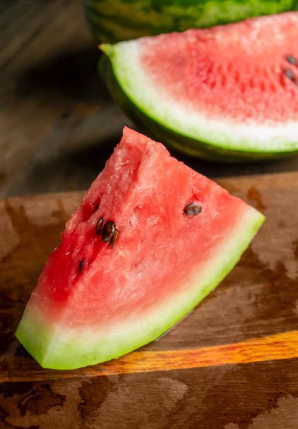 Sweet watermelon with pits on a wooden table. A triangular slice of watermelon on a wooden table. beautiful slice of watermelon. - Φωτογραφία, εικόνα