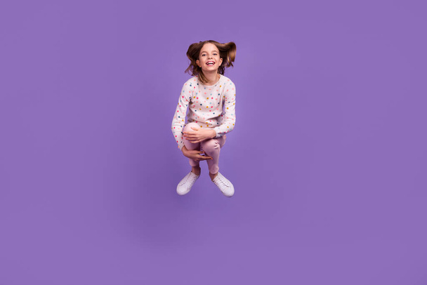 Full size portrait of overjoyed energetic pupil hands hold legs jump fall isolated on purple color background. - Φωτογραφία, εικόνα