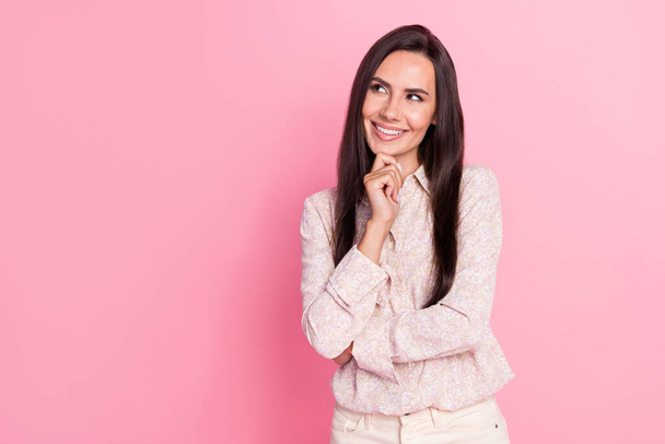Portrait photo of young smiling minded cute woman wear stylish shirt touch chin looking empty space isolated on pink color background. - 写真・画像