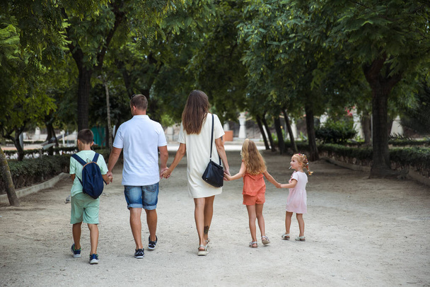 Family spending time together, cheerful parent with kids walking in the park in good weather - Foto, afbeelding