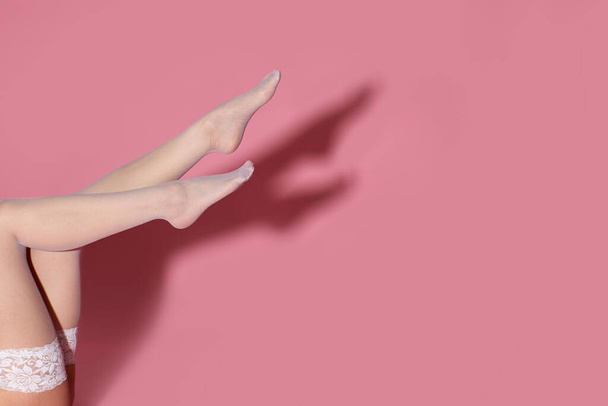 beautiful female legs in white stockings on pink background. space for text - Photo, Image