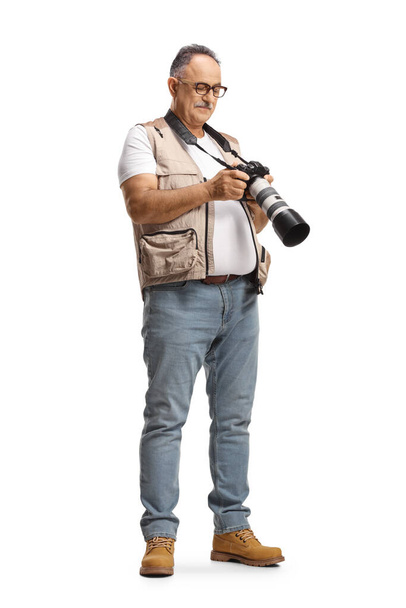 Full length shot of a mature male photographer looking at a camera display isolated on white background - Fotografie, Obrázek
