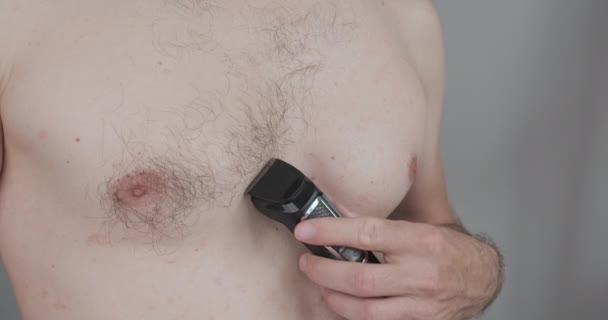 Caucasian young man shaves his chest with an electric clipper. Front view, close-up. High quality 4k footage - Filmmaterial, Video