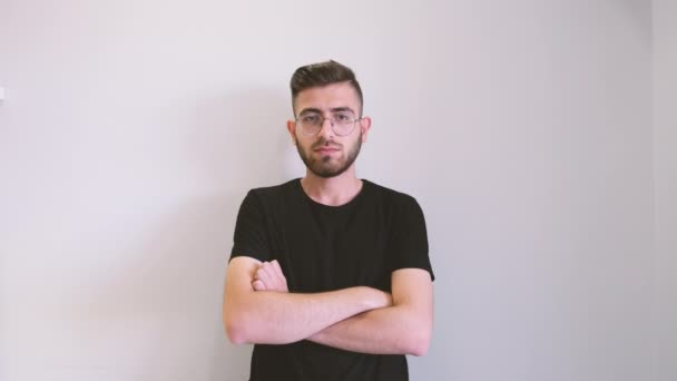 Arms crossed, portrait of young confident man arm crossed. Brown haired male wearing glasses and nodding his head constantly. Standing front of isolated white background. Facial expression concept. - Materiaali, video
