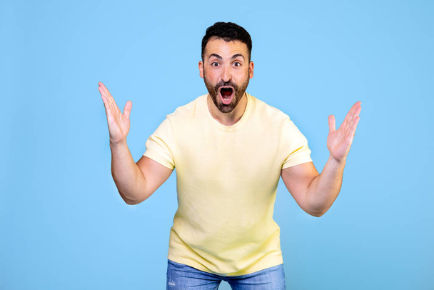 Angry and furious man on a blue background. He throws up his hands in rage and screams. High quality photo - Foto, imagen