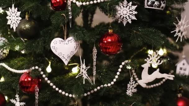 Κοντινό πλάνο χριστουγεννιάτικων διακοσμήσεων σε πράσινο χριστουγεννιάτικο δέντρο. Διακοσμητική καρδιά, νιφάδες χιονιού και άλλες διακοσμήσεις - Πλάνα, βίντεο