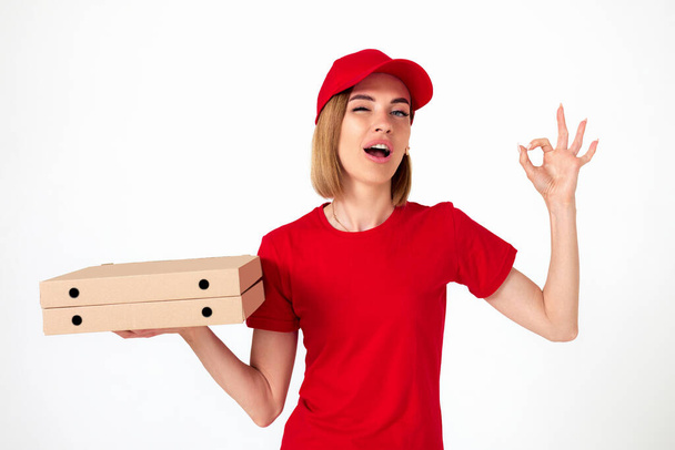 pizza delivery girl in uniform with pizza boxes showing ok gesture on white background - Fotó, kép
