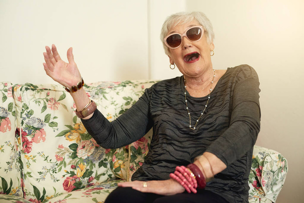 Καλώς ήρθες στην κούνια μου. Πορτρέτο μιας διασκεδαστικής ηλικιωμένης γυναίκας που ποζάρει φορώντας τα γυαλιά ηλίου της στο σπίτι - Φωτογραφία, εικόνα