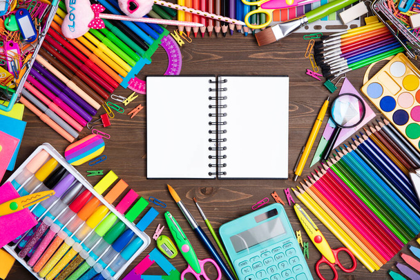 School supplies. Set of colorful school accessories isolated on the brown wooden background. Top view. - Foto, afbeelding