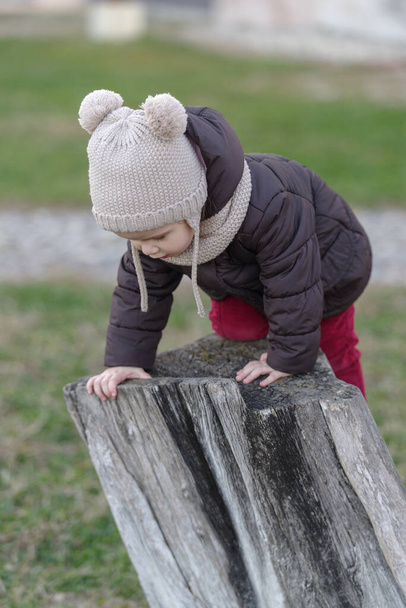 Girl playing on old tree stump in a public park - Φωτογραφία, εικόνα