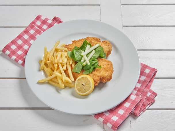 Schnitzel on the place with fried potato in the plate and sauce background. - Fotografie, Obrázek