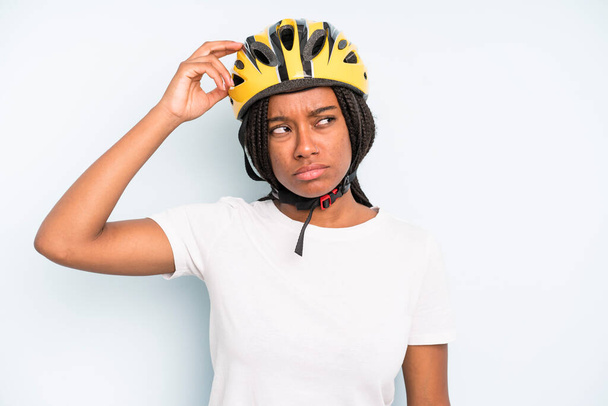 black pretty woman feeling puzzled and confused, scratching head. bike helmet concept - 写真・画像