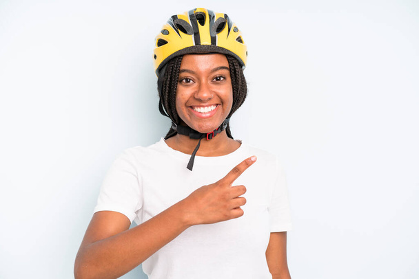 black pretty woman smiling cheerfully, feeling happy and pointing to the side. bike helmet concept - 写真・画像