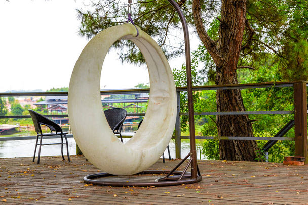 Крупним планом круглий висячий стілець у відкритому саду
 - Фото, зображення