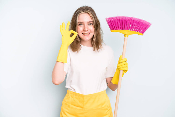 caucasian pretty woman feeling happy, showing approval with okay gesture. housekeeper cleaning concept - Fotó, kép