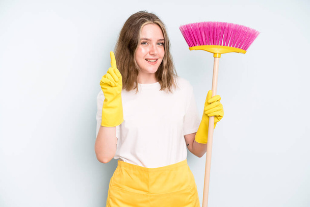 caucasian pretty woman smiling proudly and confidently making number one. housekeeper cleaning concept - Photo, image
