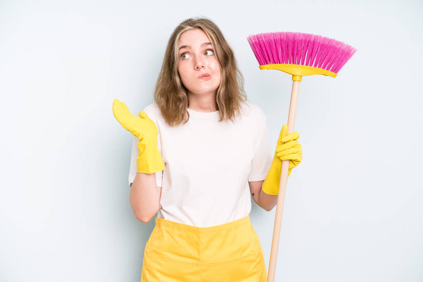 caucasian pretty woman shrugging, feeling confused and uncertain. housekeeper cleaning concept - Фото, зображення