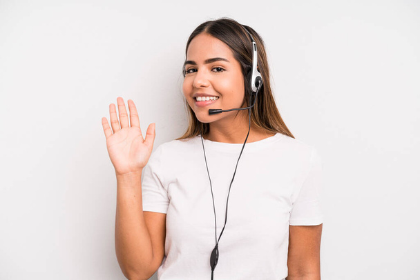 hispanic pretty woman smiling happily, waving hand, welcoming and greeting you. telemarketer concept - Foto, imagen
