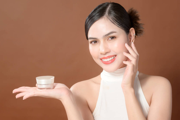A young woman with beautiful face is holding cream , using cream of her face , beauty skin care concept  - 写真・画像