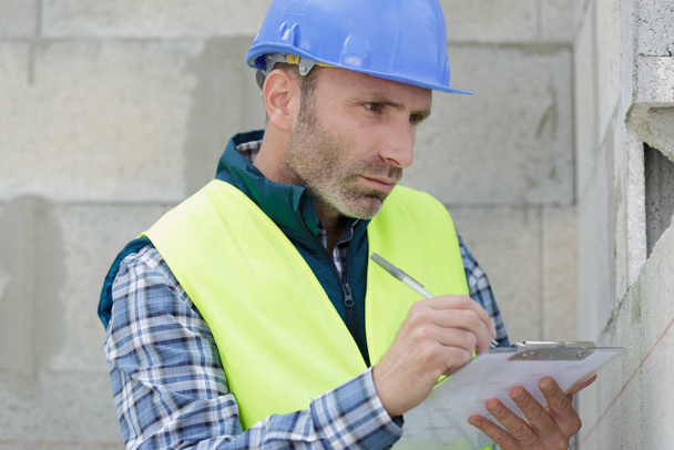 male builder writing on clipboard - Photo, Image