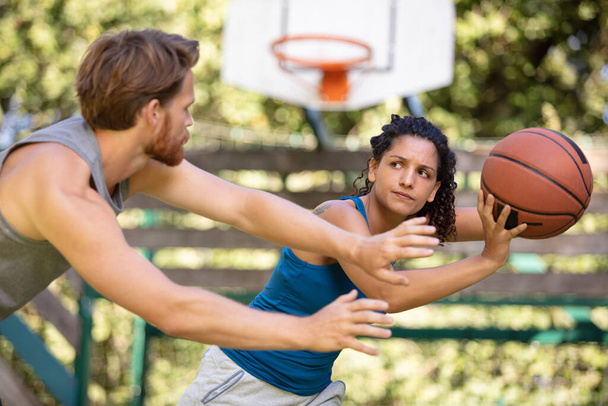 woman against a man couple playing basketball - 写真・画像
