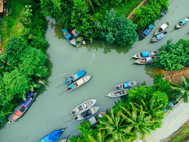 Aerial view from drones of fisherman boats and harbour in the river near the Andaman Sea in southern Thailand. Top view of many Thai traditional longtail boats floating in the mangrove landscape. - Photo, image