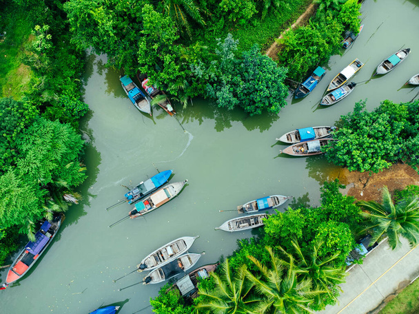 Aerial view from drones of fisherman boats and harbour in the river near the Andaman Sea in southern Thailand. Top view of many Thai traditional longtail boats floating in the mangrove landscape. - Photo, image