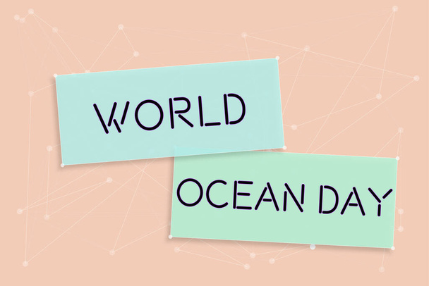 Letrero que muestra el Día Mundial del Océano, Idea de negocios Celebración mundial de grandes cuerpos de agua salada Destripador Trozo de papel con nuevas ideas con flores y clips alrededor. - Foto, imagen