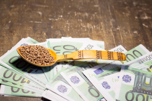 Gryka w drewnianej łyżce na banknotach euro. Rosnące ceny na Ukrainie z powodu wojny - Zdjęcie, obraz