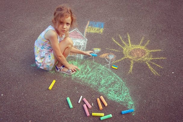 Ukrainian girl child draws children's drawings with chalk on the pavement. - Foto, Imagen