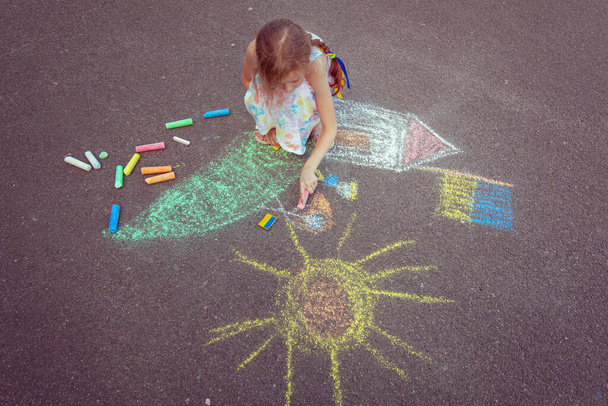 Ukrainian girl child draws children's drawings with chalk on the pavement. - Foto, immagini