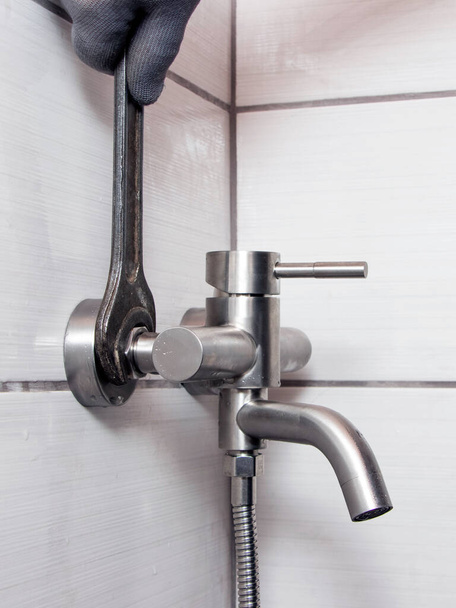 Водопроводчик с гаечным ключом устанавливает кран в ванной комнате - Фото, изображение