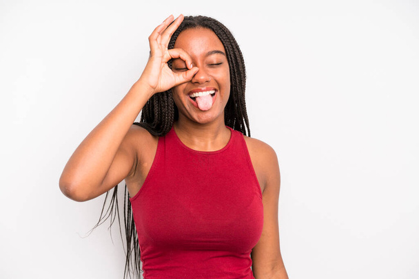 black young adult woman smiling happily with funny face, joking and looking through peephole, spying on secrets - Fotoğraf, Görsel